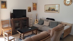 Un saló amb televisió, sofà, cadires i obres d'art a les parets.