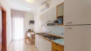 A kitchen with white cabinets, a gas stove, a sink, and a microwave. - Flat a Short Walk to the Beach (San Michele al Tagliamento)