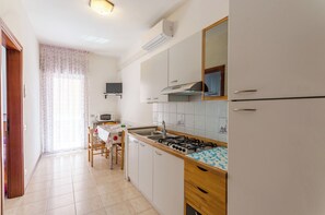 A kitchen with white cabinets, a gas stove, a sink, and a microwave. - Flat a Short Walk to the Beach (San Michele al Tagliamento)