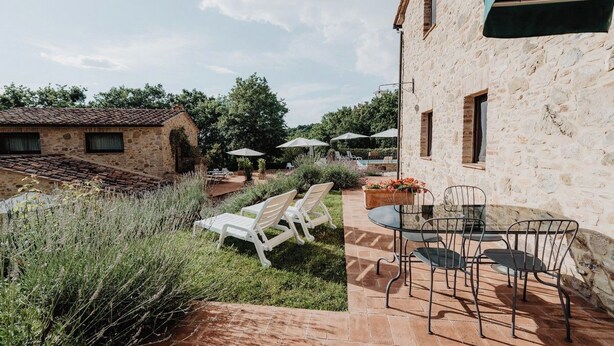 Un bâtiment en pierre doté d’un patio aménagé avec des espaces de détente en plein air et des parasols.
