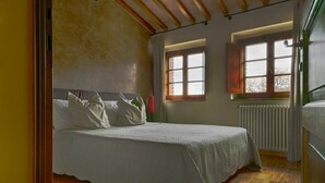 A bedroom with a bed, two windows, and a radiator. - Four-room flat 6/8 sleeps Nr 4 (Cornocchia)