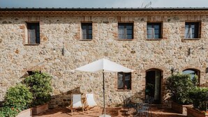 A stone building with a tiled roof, outdoor seating area with chairs and an umbrella, and potted plants. - Four-room flat 6/8 sleeps Nr 4 (Cornocchia)