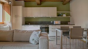 Una cocina moderna con armarios blancos, un comedor con mesa y sillas, y un sofá con un cojín.