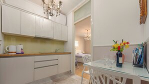 A modern kitchen with white cabinets, a wooden countertop, and a glass dining table with white chairs. - Apartment Oasis with Sea View (Zadar)