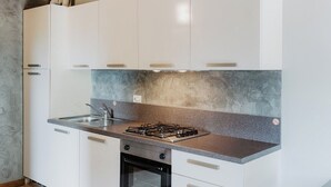 Uma cozinha moderna com armários brancos, bancada de granito, fogão a gás e forno embutido.