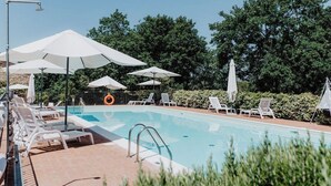Piscina com guarda-sóis, espreguiçadeiras e boia.