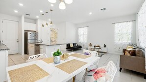 Uma cozinha moderna com armários brancos, uma ilha central e iluminação pendente.