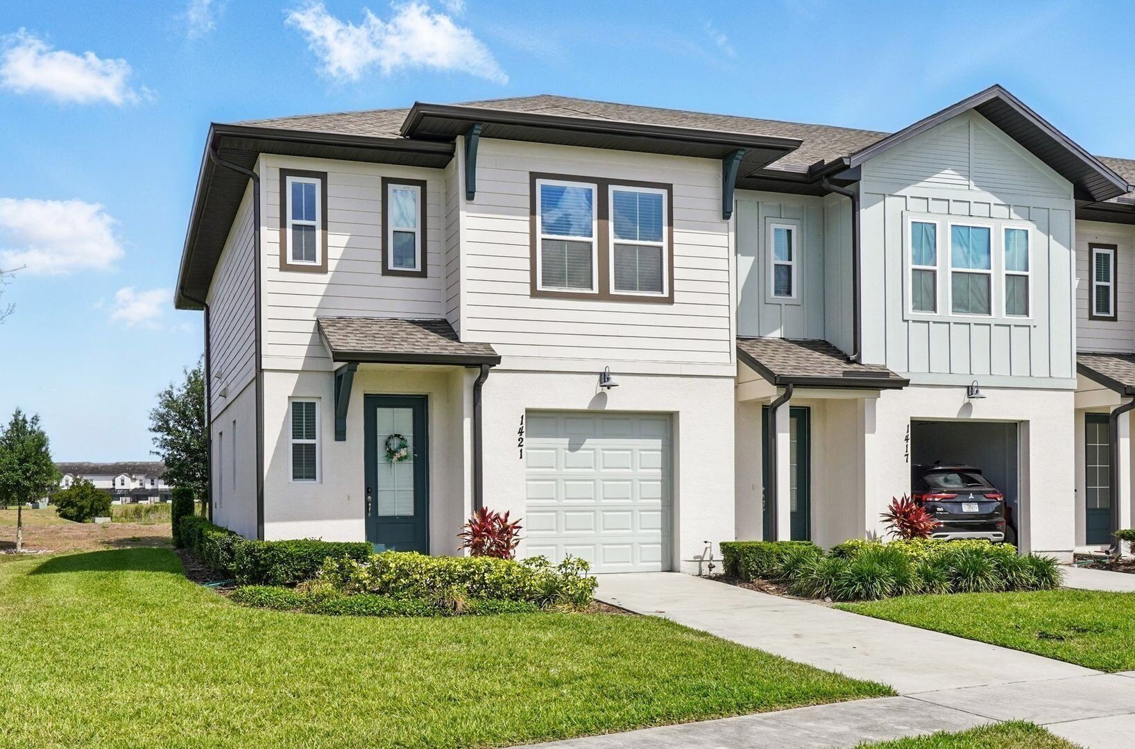A two-story residential building with a front garage and a driveway.