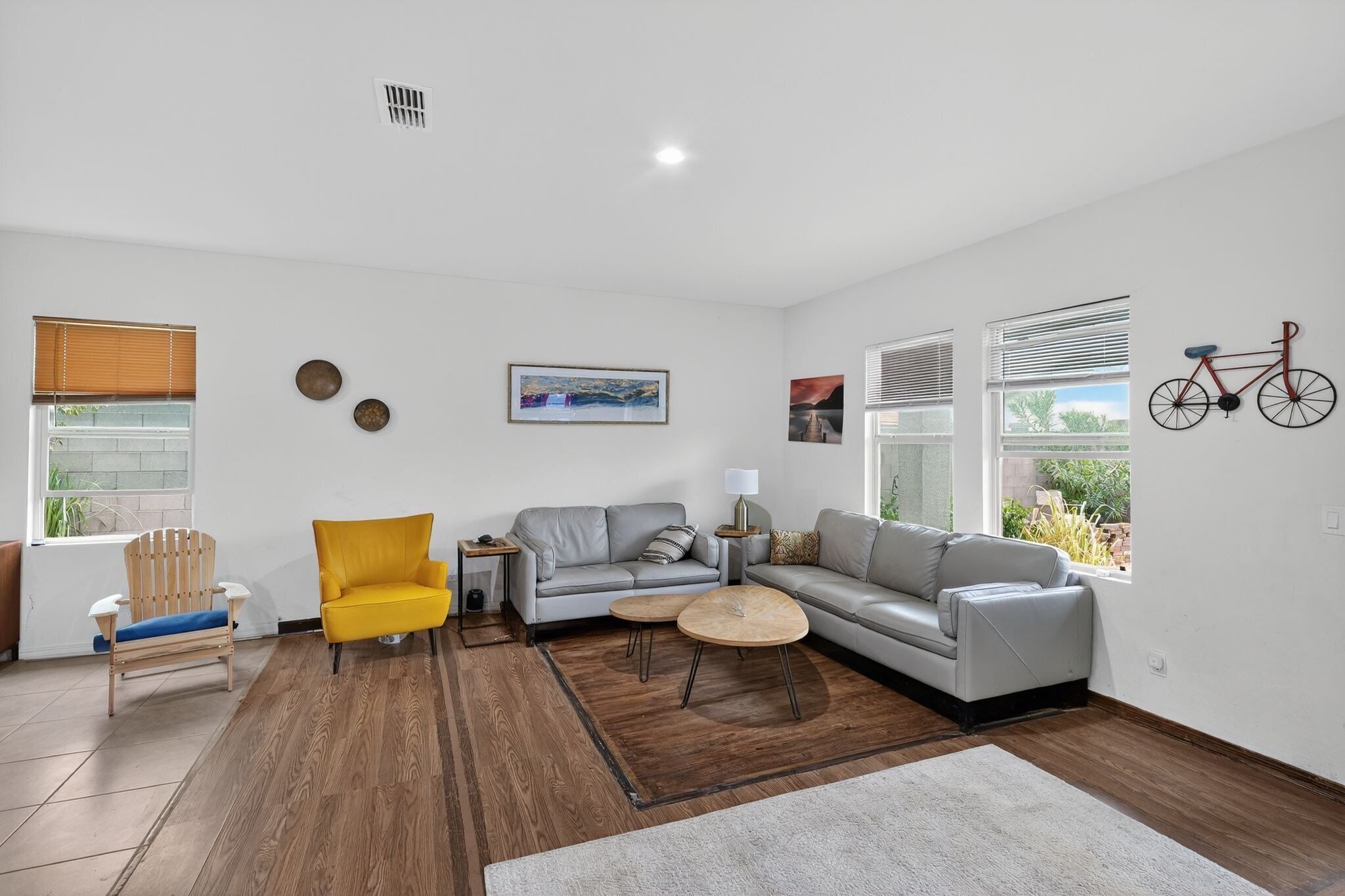 A modern living room with a sofa, armchairs, a coffee table, and a bicycle wall decoration.