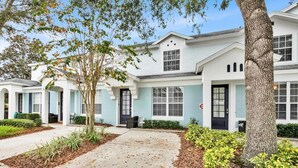 A row of modern, two-story townhouses with light blue and white exteriors, front porches, and a well-maintained garden area. - Windsor Hills Resort 3 Bedroom Private Pool Townhome 3 Townhouse (Kissimmee)