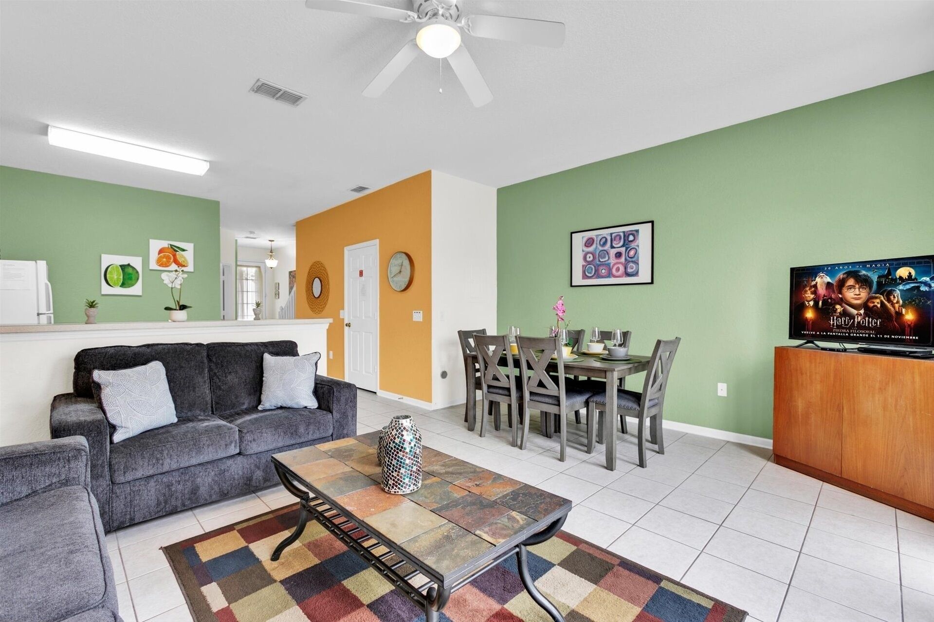 A living room with a gray sofa, a coffee table, and a dining area with a table and chairs.