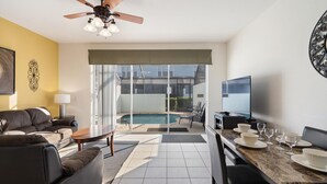 A modern living room with a pool, a dining area, and a TV. - Windsor Hills 3 Bedroom Private Pool Townhome 3 Townhouse (Kissimmee)