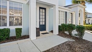 A modern two-story house with a front entrance, a dark blue door, and a small porch area. - Windsor Hills 3 Bedroom Private Pool Townhome 3 Townhouse (Kissimmee)