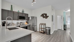 A modern kitchen with grey cabinets, stainless steel appliances, and a central island. - Windsor Hills Resort 3 Bedroom Private Pool Townhome 3 Townhouse (Kissimmee)