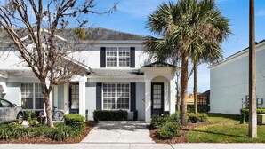 A two-story house with a front porch, a garage, and a driveway. - Windsor Hills 3 Bedroom Private Pool Townhome 3 Townhouse (Kissimmee)