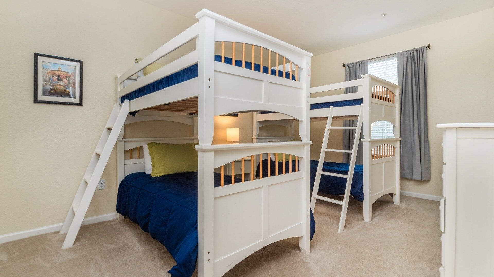 A bunk bed room with a ladder, a small table, and a window with curtains.
