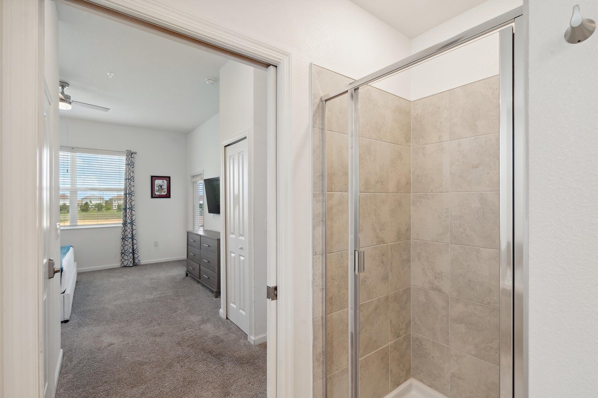 A modern bathroom with a glass shower enclosure, a vanity with a mirror, and a window with blinds.