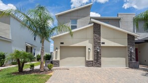 A modern two-story house with a garage, numbered 977 and 979, featuring a stone accent wall and a paved driveway.