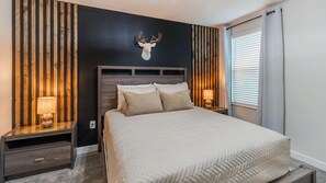A bedroom with a bed, two bedside tables, a wall-mounted lamp, and a deer head decoration. - Championsgate Resort 8 Bedroom Private Pool Home 8 Home (Davenport)