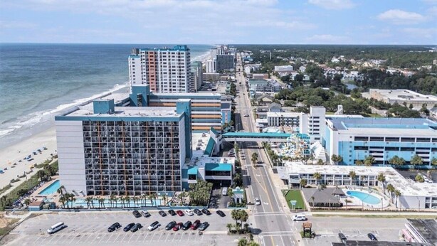 Un hôtel situé sur la côte, composé de plusieurs bâtiments, doté d’un parking et offrant une vue sur la plage.