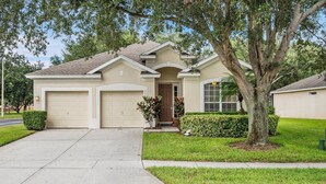 A single-story house with a front garage, a covered entryway, and a well-maintained lawn. - Windsor Hills Resort 4 Bedroom Home with Pool+Spa 4 Home (Kissimmee)