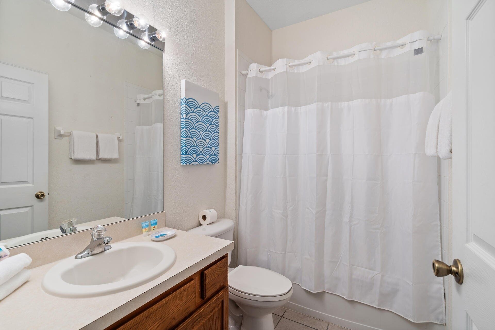 A bathroom with a sink, mirror, vanity, and toilet.