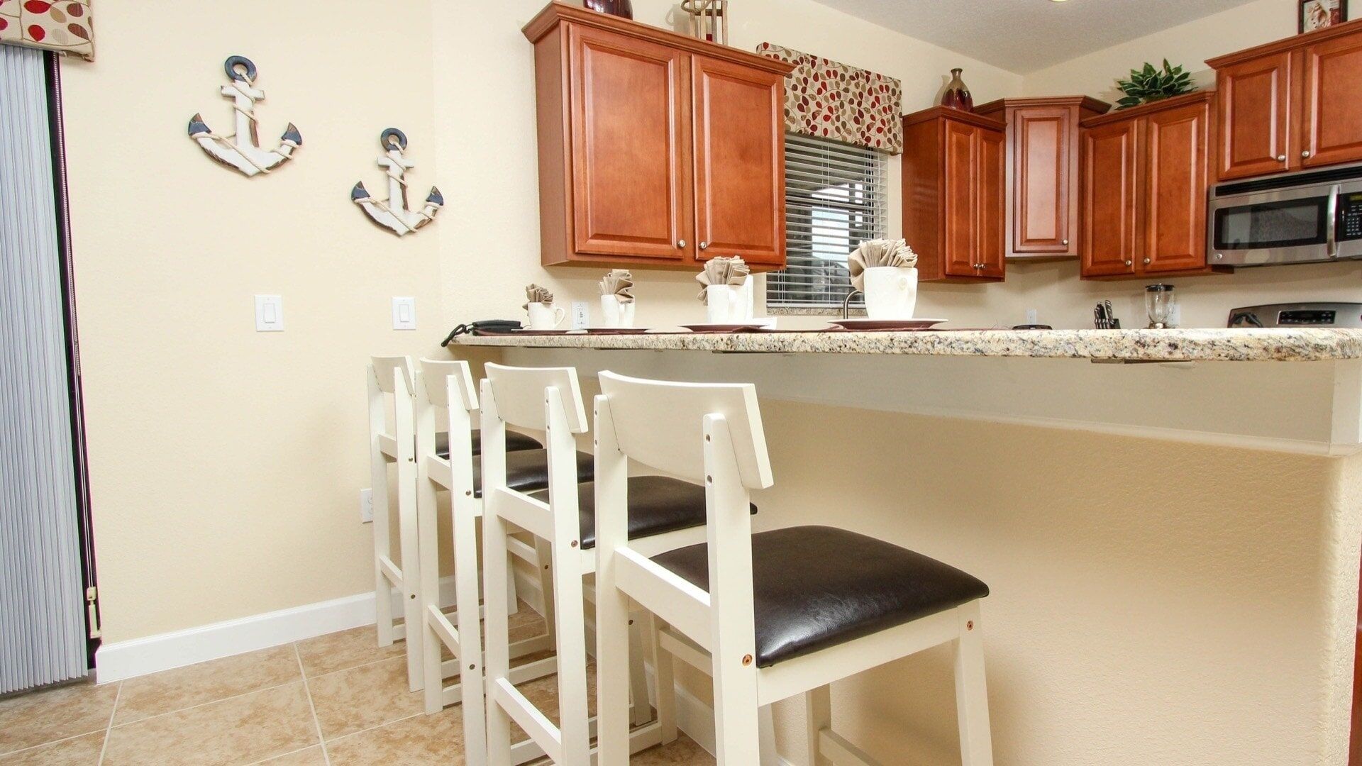 A kitchen with wooden cabinets, a granite countertop, and white bar stools.