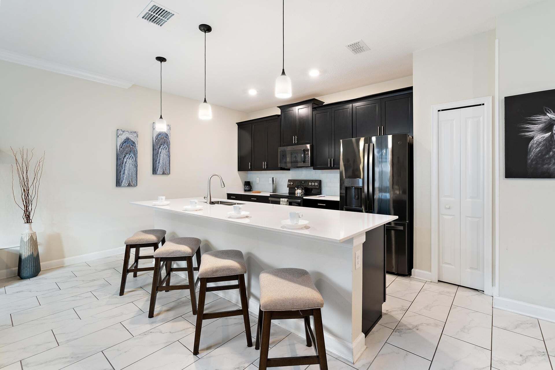 A modern kitchen with a central island, dark cabinetry, stainless steel appliances, and pendant lighting.