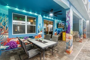 An outdoor dining area with a table and chairs, surrounded by vibrant mural art. - ChampionsGate Resort 8-Bedroom Vacation Pool Home - Includes Resort Clubhouse Amenity Access! 8 Home (Kissimmee)