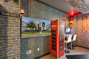 A train ticket sign, a telephone booth, and a welcome sign in a lobby with a stone wall and a modern building outside. - ChampionsGate Resort 8-Bedroom Vacation Pool Home - Includes Resort Clubhouse Amenity Access! 8 Home (Kissimmee)