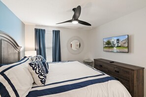 A bedroom with a bed, a ceiling fan, a wall-mounted TV, and a dresser. - ChampionsGate Resort 8-Bedroom Vacation Pool Home - Includes Resort Clubhouse Amenity Access! 8 Home (Kissimmee)