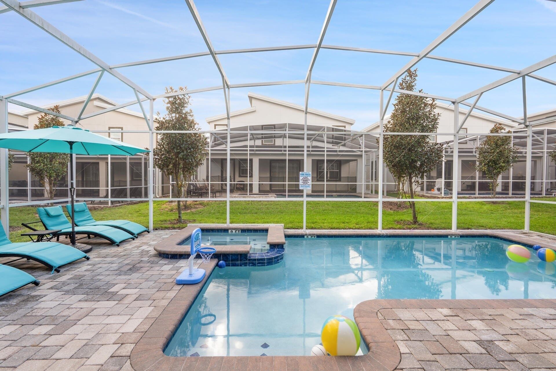 A pool area with a hot tub, lounge chairs, and a covered patio.