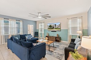 A living room with a sofa, coffee table, and a TV mounted on the wall. - ChampionsGate Resort 8-Bedroom Vacation Pool Home - Includes Resort Clubhouse Amenity Access! 8 Home (Kissimmee)