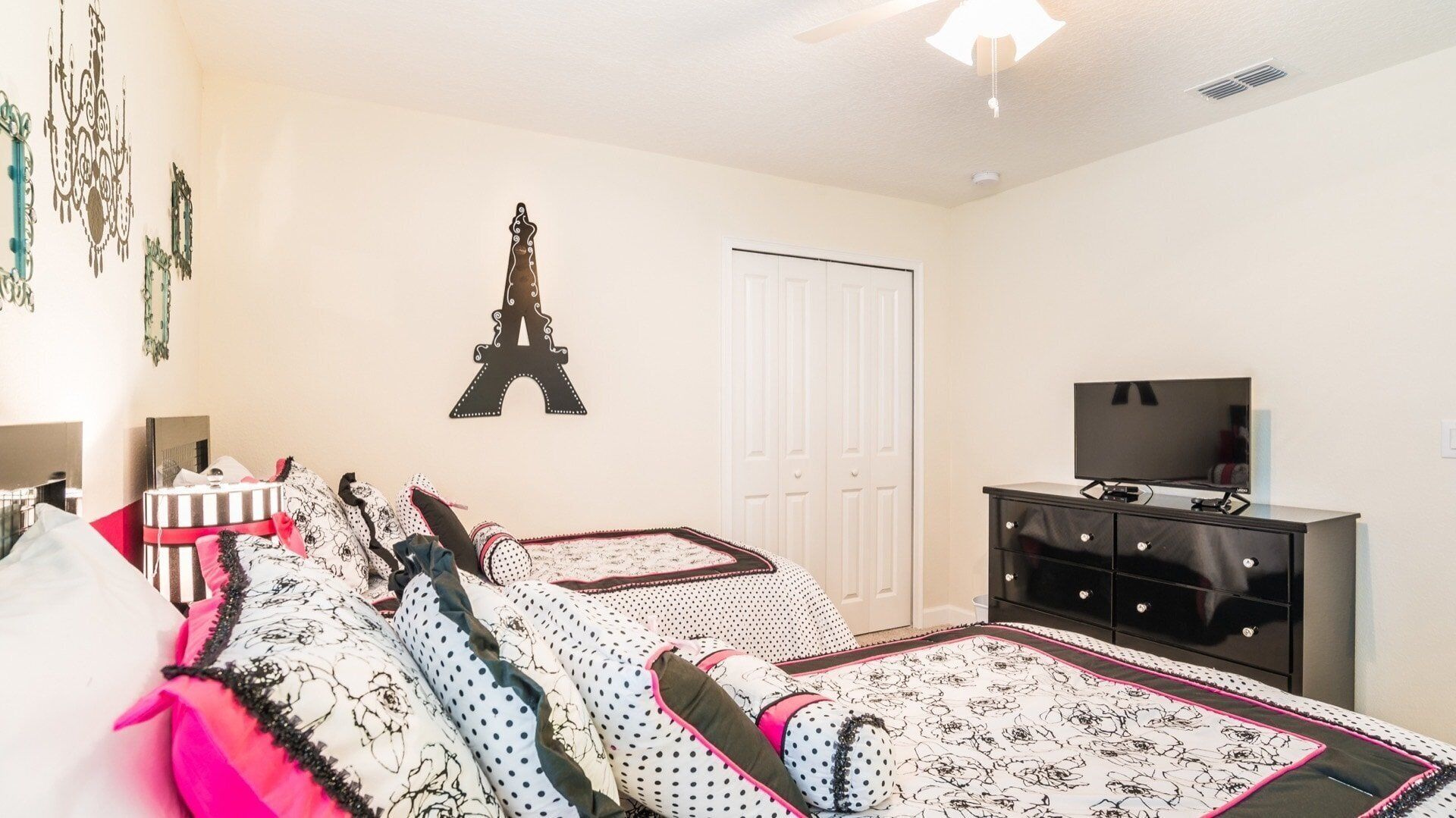 A bedroom with two beds, a dresser, a TV, and a door.