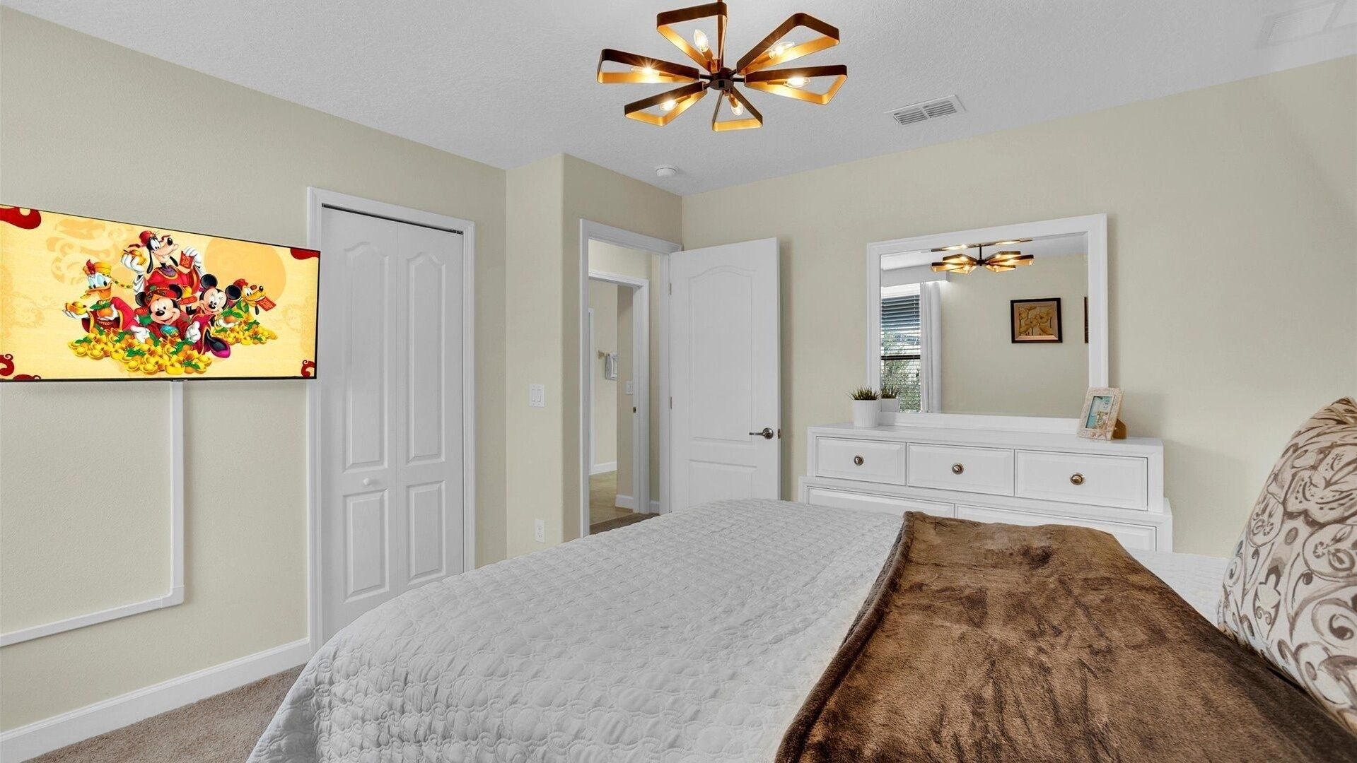 A bedroom with a bed, a dresser, a mirror, and a ceiling light fixture.