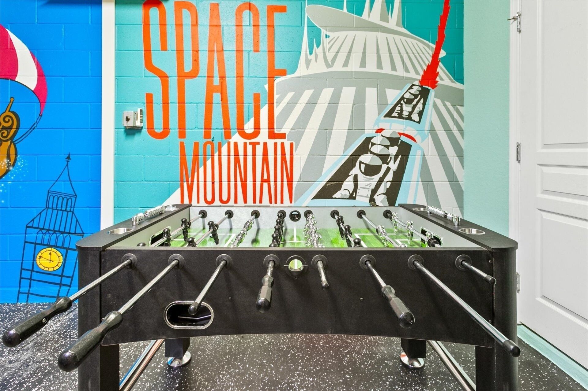 Una mesa de fútbol de mesa con un mural con temática espacial al fondo.