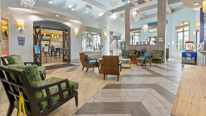 Un'ampia hall con soffitti alti, lampadari moderni e diverse zone relax con divani e poltrone.