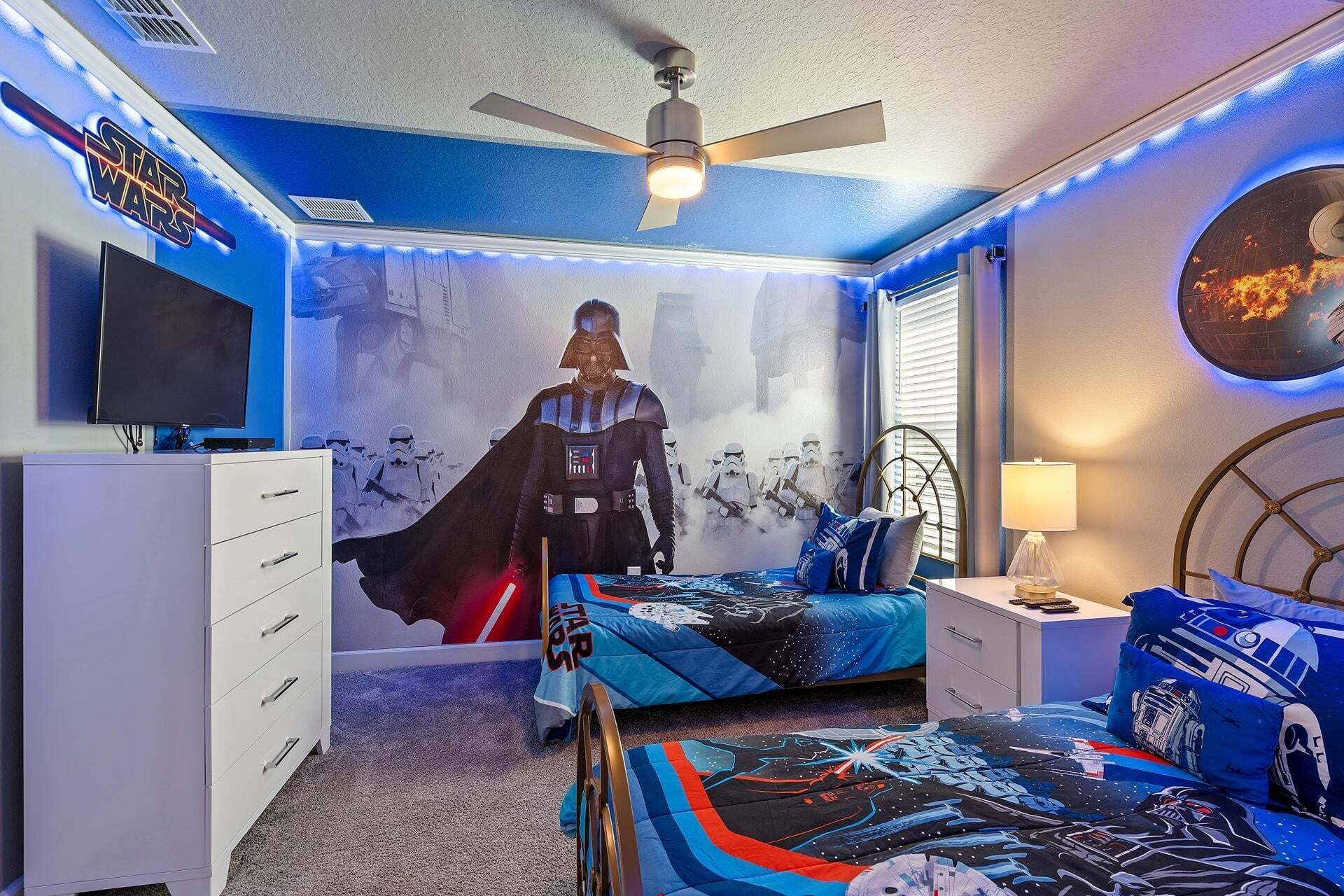 A Star Wars-themed bedroom with a bed, dresser, and ceiling fan.