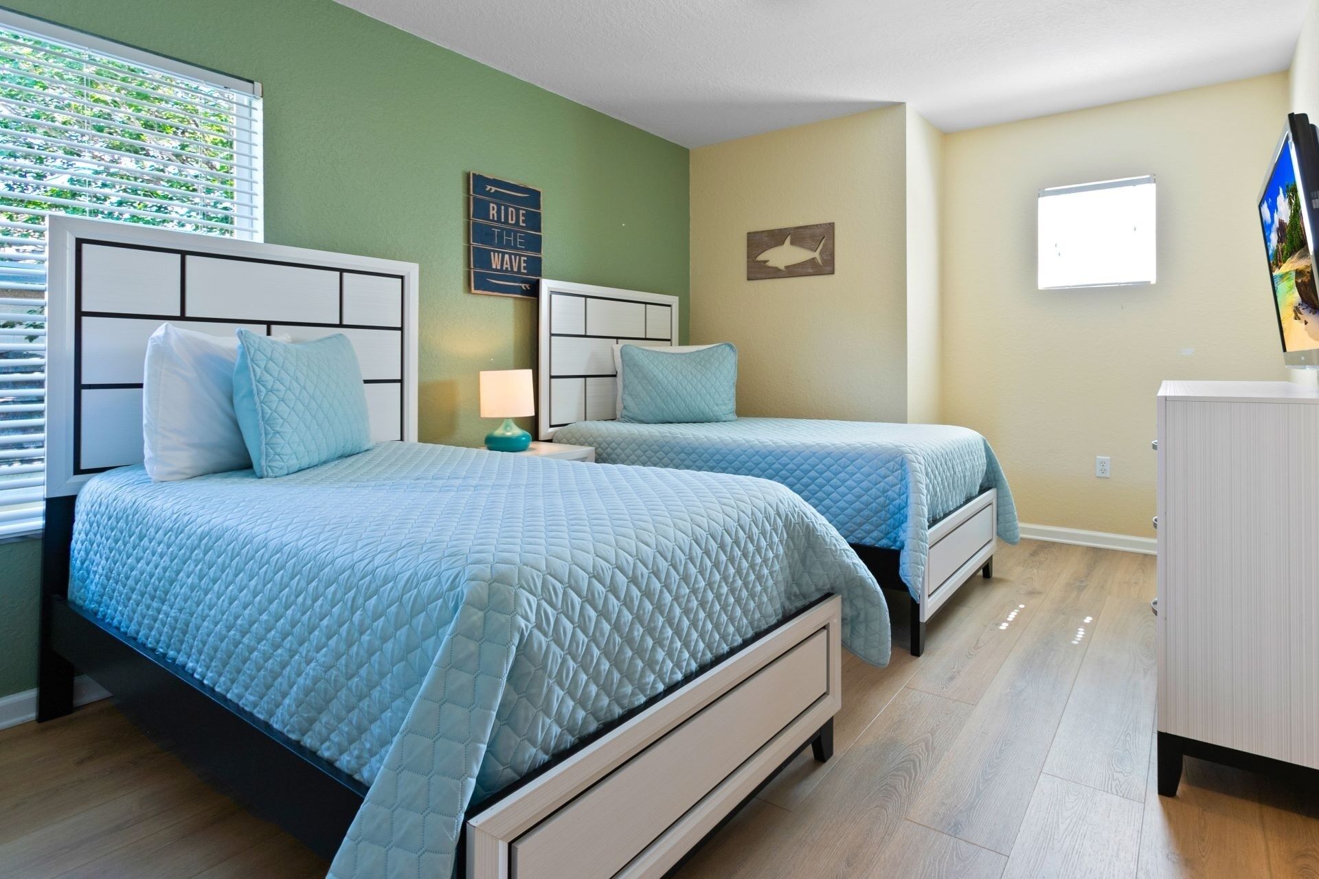 A bedroom with two beds, a nightstand, a lamp, and a small cabinet.