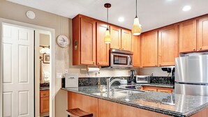 A kitchen with wooden cabinets, a granite countertop, a stainless steel refrigerator, and a microwave. - Chamonix 33: Close to Canyon Lodge (Mammoth Lakes)