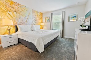 Un dormitorio con una cama grande, dos mesitas de noche con lámparas, un aparador y una pared con diseño de hojas.