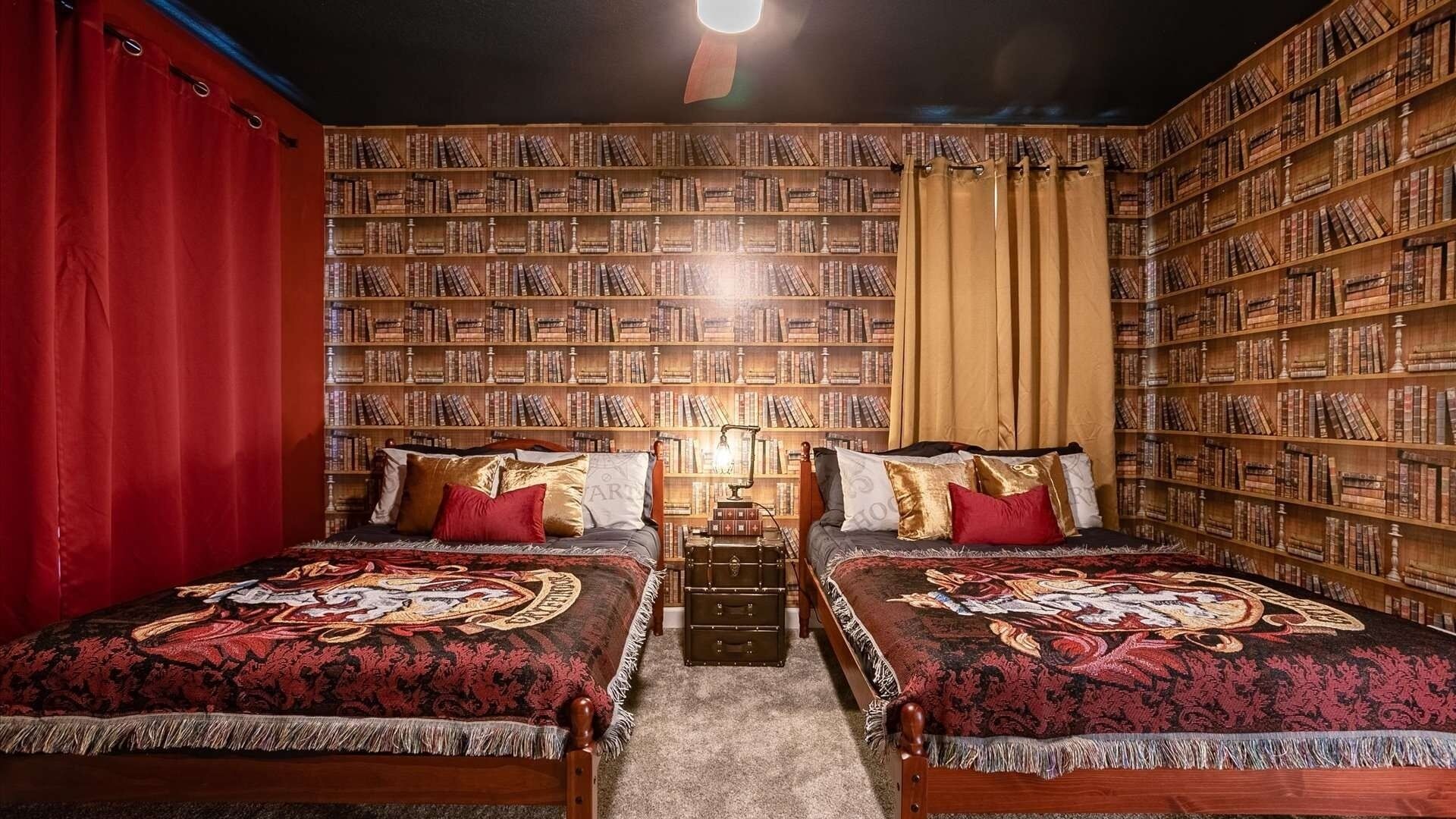 A room with two beds, a bookshelf, and a desk with a lamp.