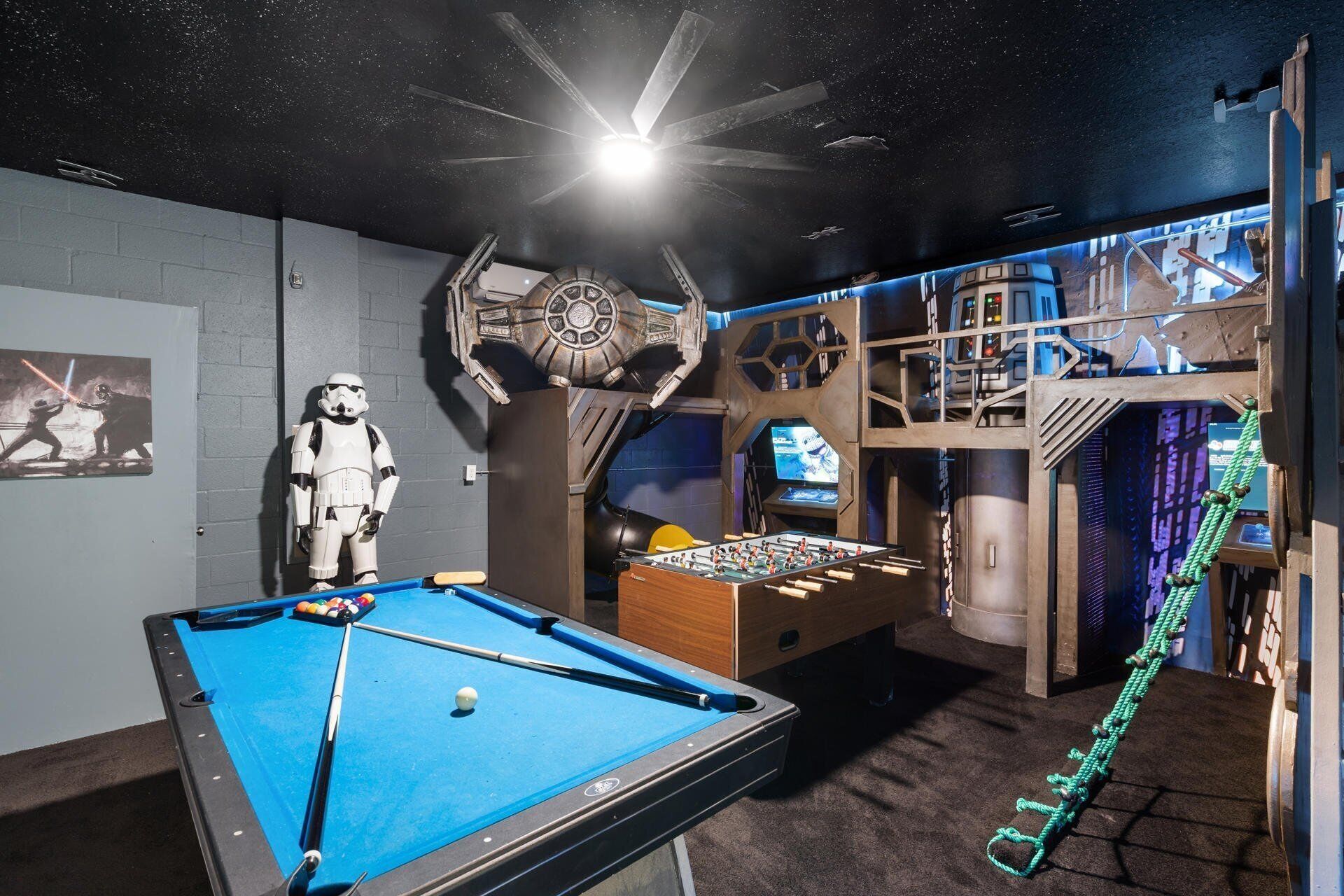 Ein Zimmer mit Poolbillard, einer Star Wars-Dekoration und einem Kicker.