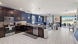 Een moderne keuken met donkere kastjes, een groot eiland en een eetgedeelte met uitzicht.