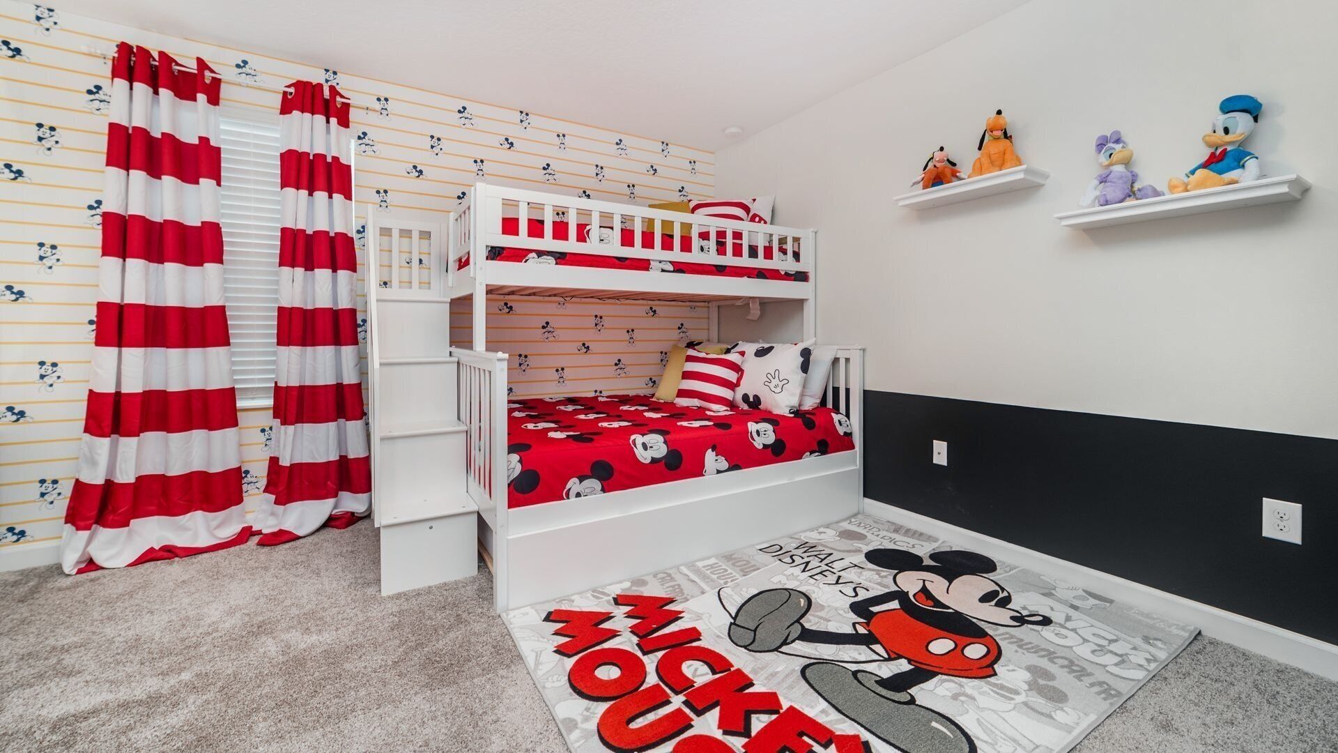 Une chambre d’enfant avec un lit superposé, de la literie aux motifs de Mickey Mouse et un tapis à l’effigie de Mickey Mouse.