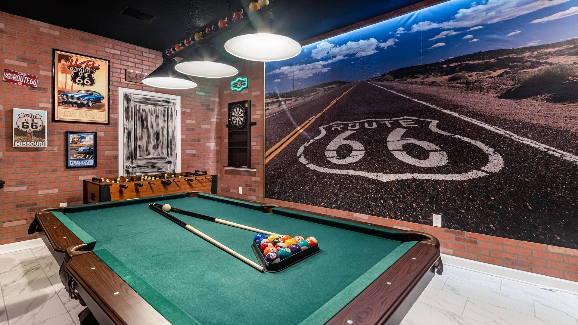 A pool table with a mural of Route 66, a dartboard, and various Route 66 memorabilia on the walls.