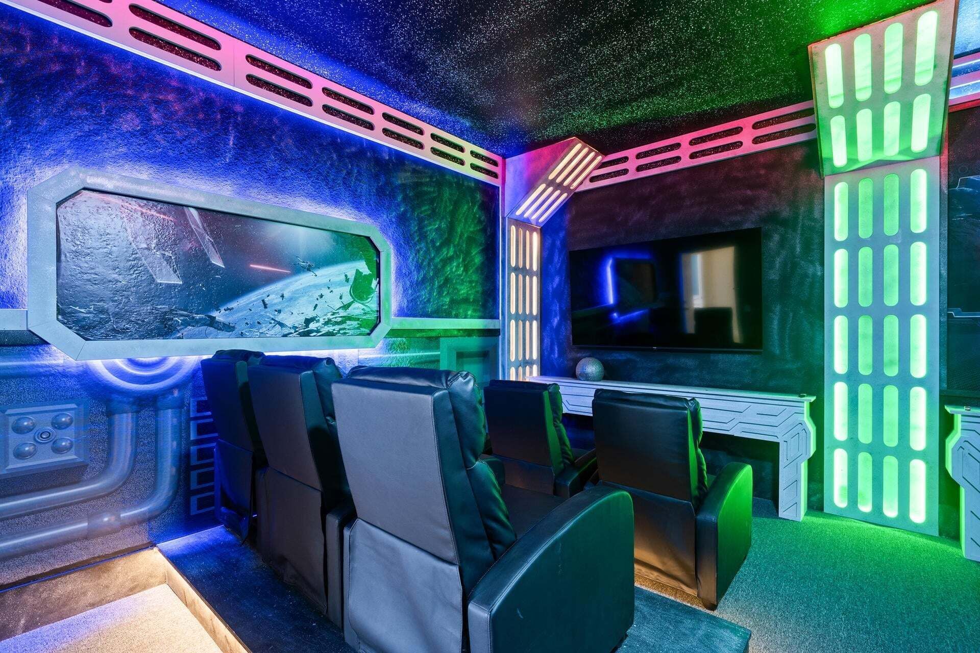 A room with a large screen, seating, and a control panel.