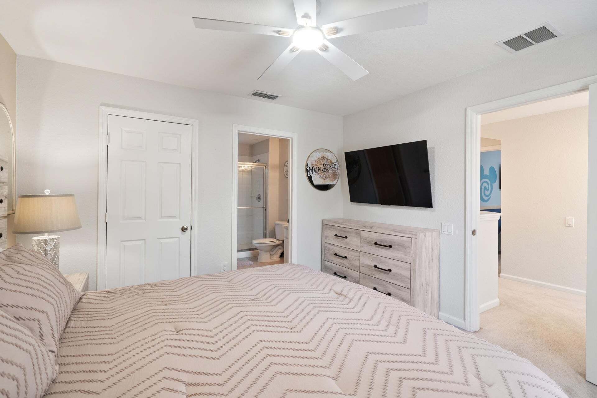 A bedroom with a bed, a dresser, a TV, and a closet.