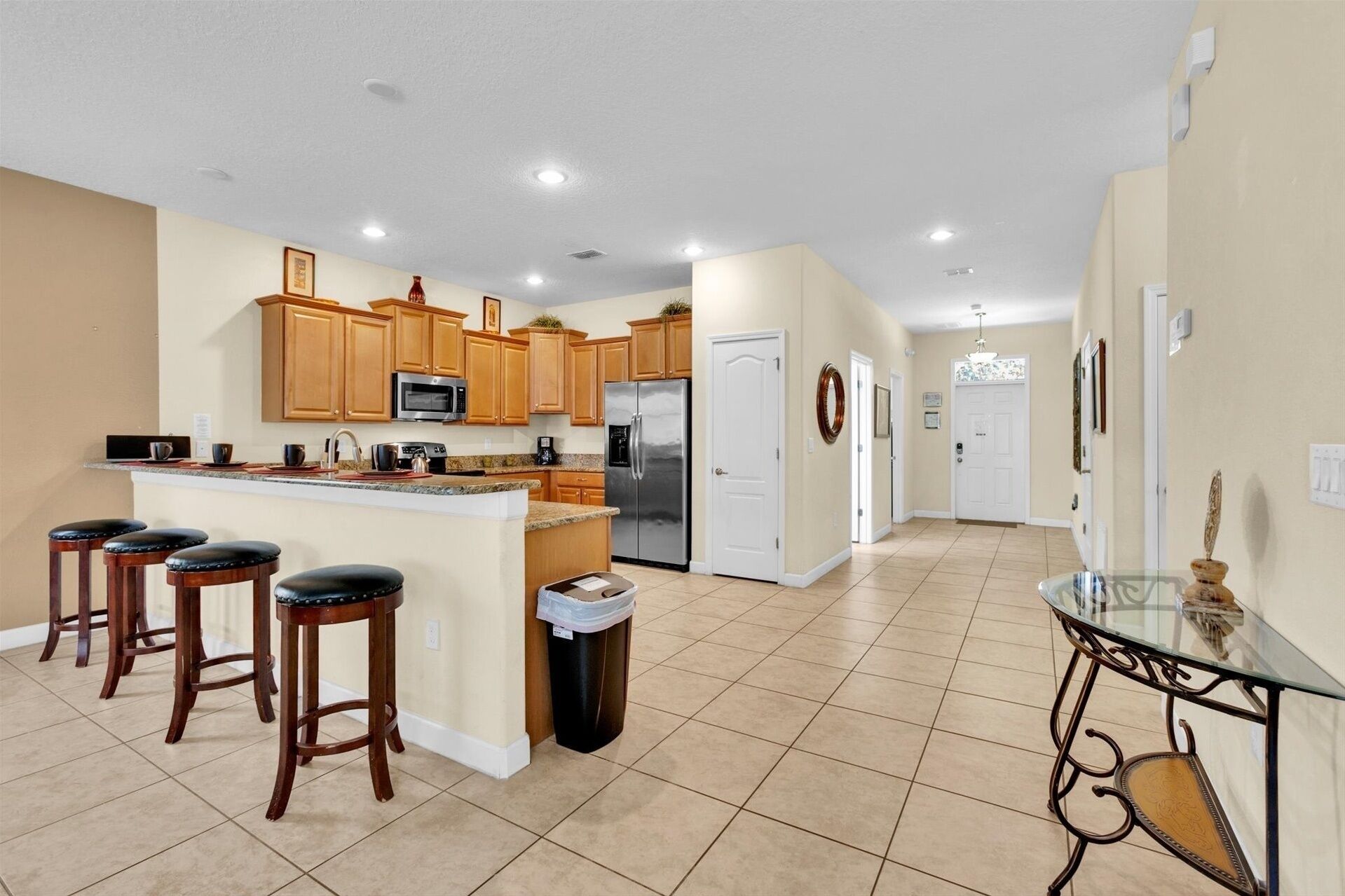 A spacious kitchen with wooden cabinets, a stainless steel refrigerator, and a granite countertop.