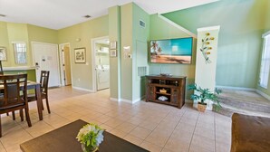 A living room with a dining area, a TV, and a staircase leading to another level. - Emerald Island Resort 3 Bedroom Townhome Close to Disney! 3 Townhouse (Kissimmee)